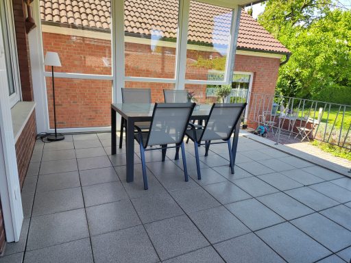 Ein gedeckter Tisch mit Stühlen auf einer überdachten Terrasse.